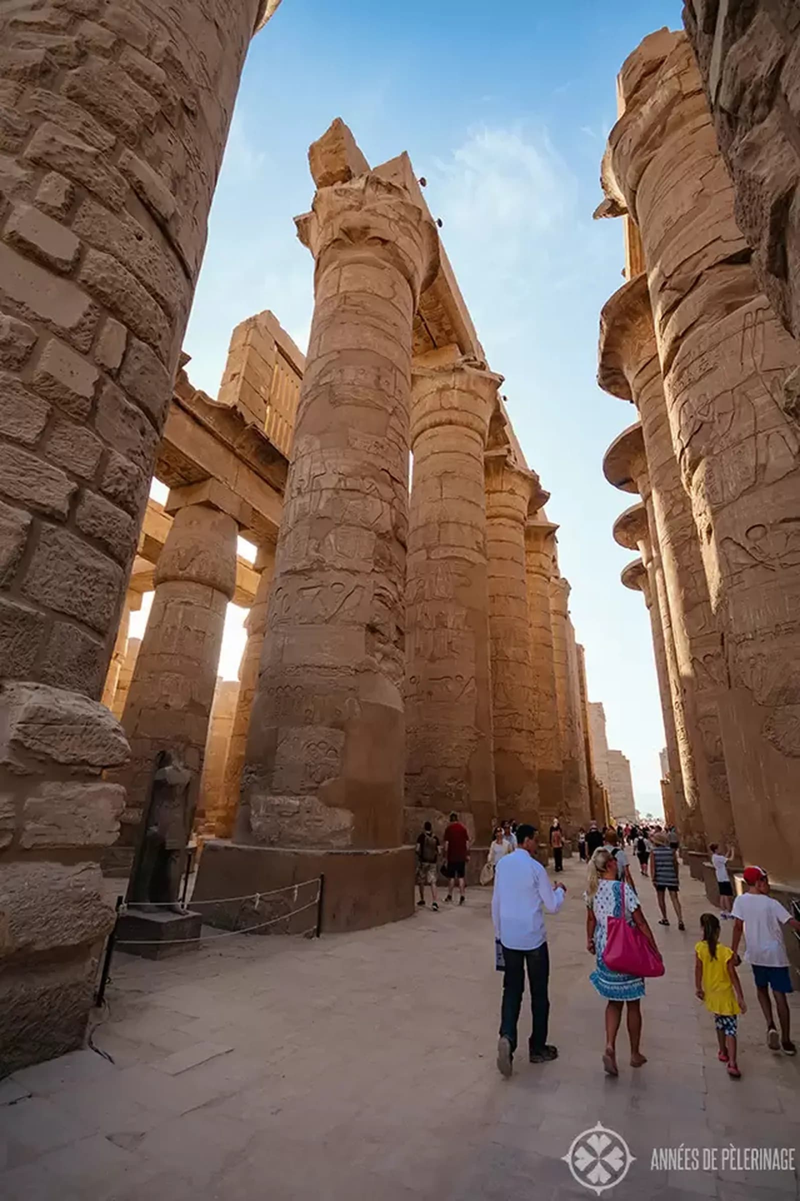 A view up through the columns of Luxor Temple toward a bright sky.