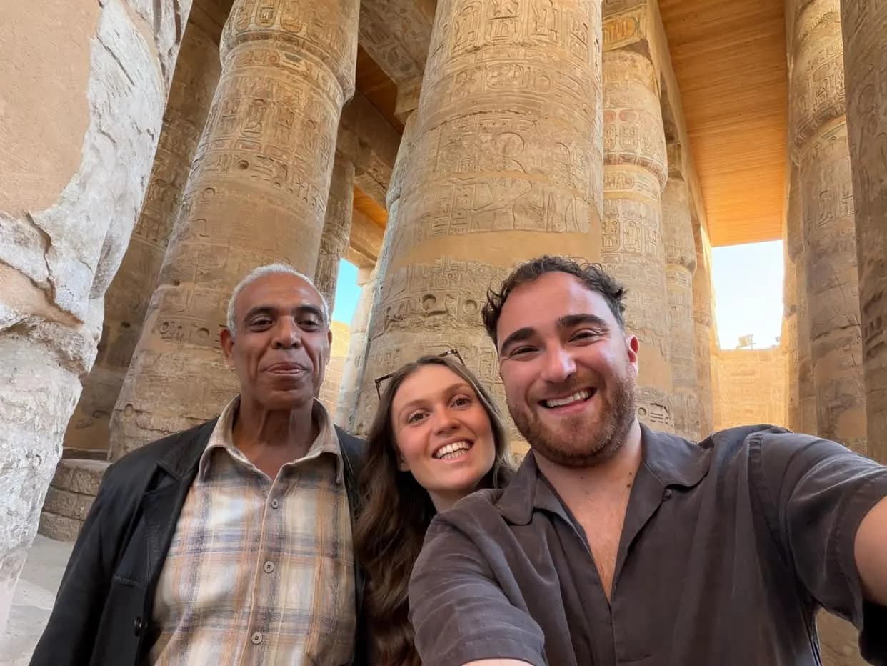 Smiling travelers taking a selfie with their guide among Karnak's columns