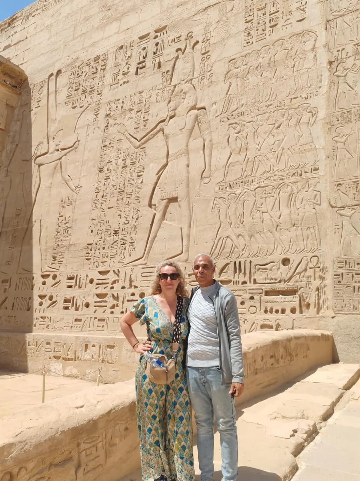 A traveler and guide posing by carved battle reliefs at Medinet Habu, Luxor
