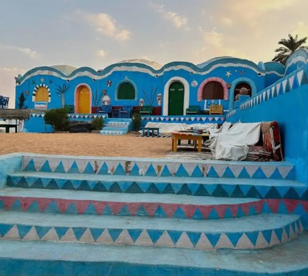 A blue-painted Nubian-style village house with decorated steps at dusk